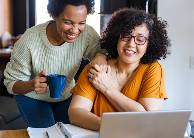 Two smiling girls looking at the computer